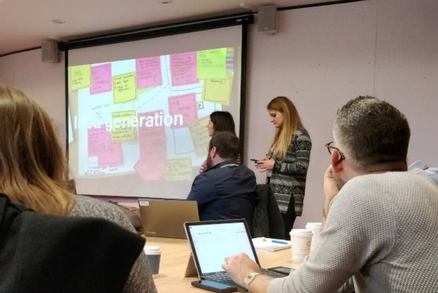 A meeting room showing 5 members of the community looking at a slide saying 'Idea generation'.