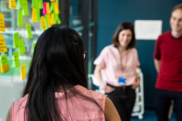 Image showing three people in a workshop, with post-its on the window.