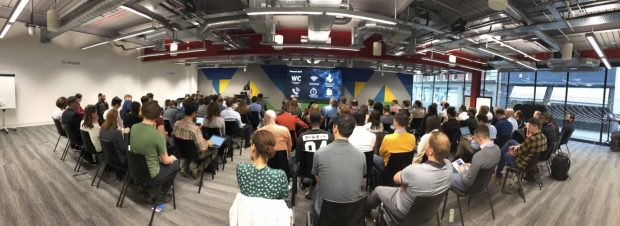 Wide-angle shot of around 100 people watching a presentation