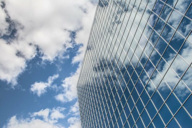 The glass windows of a tall office building reflecting the sky, with no transparency