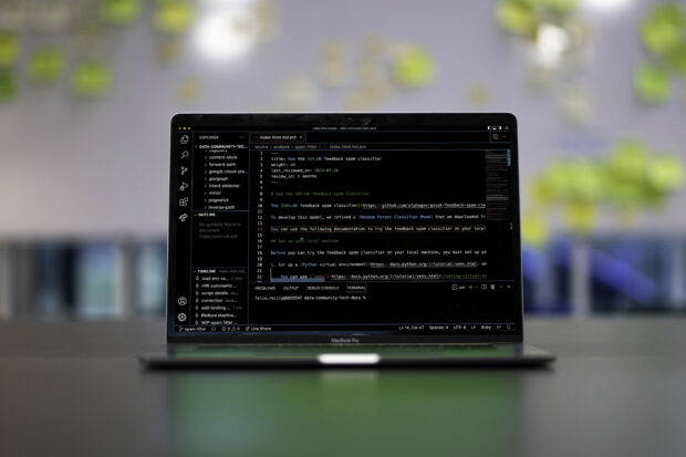 A laptop on a desk with the background blurred. n the laptop screen is an interactive development environment window with some code visible.