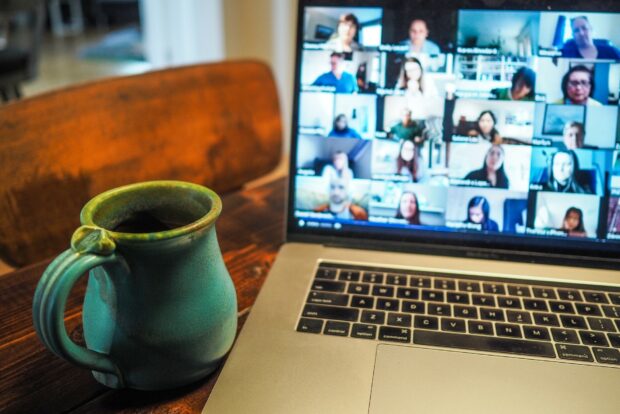 A mug next to a laptop featuring a group of people on a virtual call