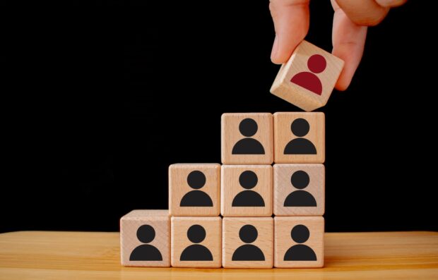 A picture of building blocks being picked up representing individuals within the structure of an organisation