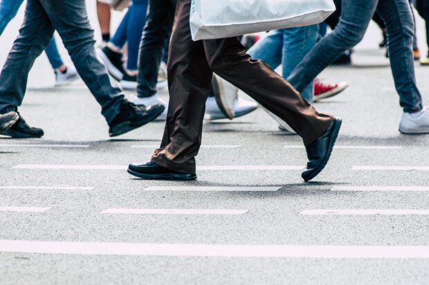 Photo of people's legs, walking along a high street with shopping bags.